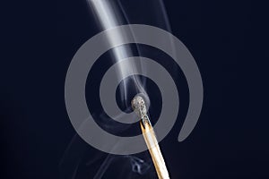 Extinguished match with smoke on dark blue background
