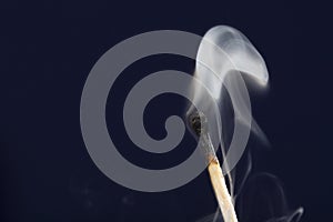 Extinguished match with smoke on dark blue background
