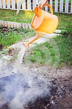 Extinguishing the fire with water from a watering can at the dacha