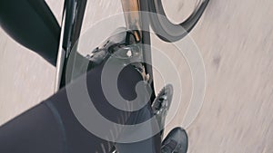 Extra close up view of male sportive leg is riding on road bike. Professional cyclist in black cycling apparel pedaling on road bi