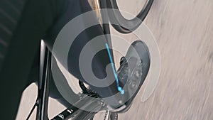 Extra close up view of male sportive leg is riding on road bike. Professional cyclist in black cycling apparel pedaling on road bi