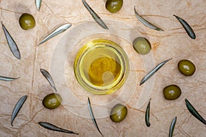 Extra virgin olive oil in glass bowl. It includes olive leaves and branches. Rustic Background. Top view