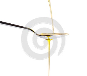 Extra virgin olive oil pouring over a spoon isolated on white background