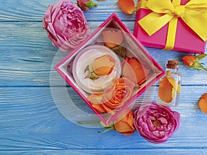 Extract, essence gift box cosmetic product bow composition cream beautiful fresh orange rose on a blue wooden background