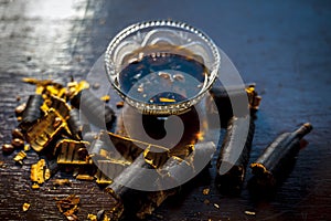 Extracted water of garmalo or indian shower tree in a glass bowl on wodoen surface with sugar and raw garmalo or amaltas.