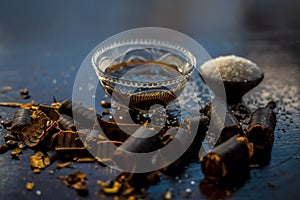 Extracted water of garmalo or indian shower tree in a glass bowl on wodoen surface with sugar and raw garmalo or amaltas.