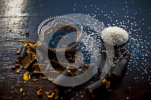 Extracted water of garmalo or indian shower tree in a glass bowl on wodoen surface with sugar and raw garmalo or amaltas.