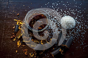 Extracted water of garmalo or indian shower tree in a glass bowl on wodoen surface with sugar and raw garmalo or amaltas.