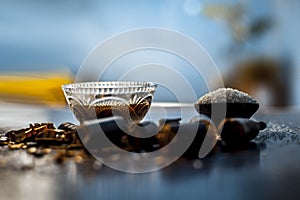 Extracted water of garmalo or indian shower tree in a glass bowl on wodoen surface with sugar and raw garmalo or amaltas.