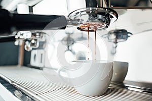 Extraction of espresso from bottomless portafilter in white cup photo