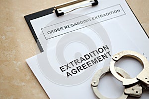Extradition Agreement and Order Regarding Extradition with handcuffs on table