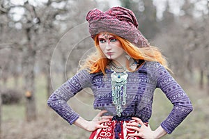 Extravagant redhead woman in ethnic national dress dancing or posing in a mistical forest photo