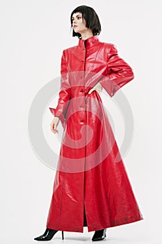 Extravagant woman in a red coat looks aside