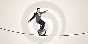 Extreme business man riding unicycle on a rope