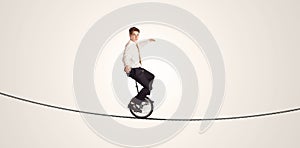Extreme business man riding unicycle on a rope