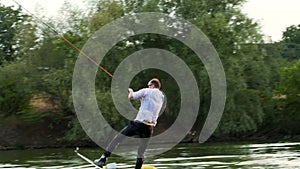 Extreme businessman in a suit with sunglasses rides on wakeboard and jumping on a springboard on a lake