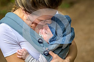 Extreme close up of a baby sleeping in a baby carrier on his mother's chest