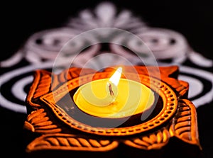 Extreme close up of beautiful shining terracotta lamp and white rangoli on black background. diwali concept