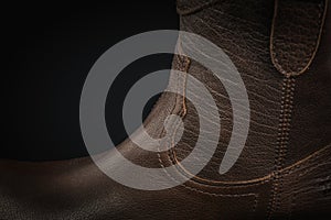 Extreme close-up of a brown leather cowboy boot on black