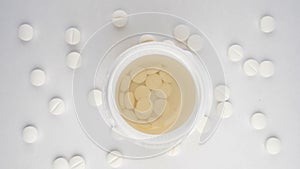 extreme close-up, detailed. pills poured into a jar, top view, white background