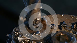 Extreme close-up of drilling machining process in metal part on a lathe, water is pouring on drill, manufacturing