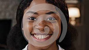 Extreme close up female face with perfect skin healthy millennial african woman looking at camera indoors happy 20s 30s