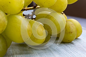 Extreme close-up of green grapes to produce white wine, on wooden table