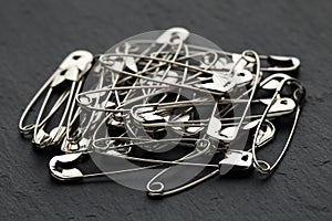 Extreme close up of a heap of safety pins on a black stone background