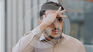 Extreme close-up idiotic male face funny humorous Arabic business man Hispanic guy boss manager worker holds hand near