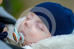 Extreme close up of little baby sleeping with a pacifier and a blue hat