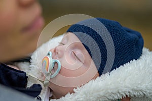 Extreme close up of little baby sleeping with a pacifier and a blue hat