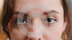 Close-up macro portrait of young woman face smiling, brunette girl eyes looking at camera blink wink