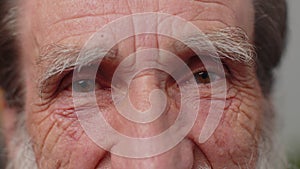 Extreme close-up macro portrait of wrinkled face, old senior beautiful man's eyes looking at camera