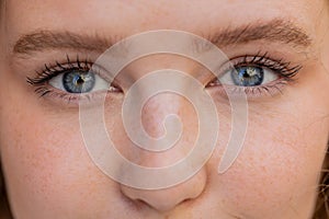 Extreme close-up macro portrait of young smiling redhead face, pretty woman's eyes looking at camera