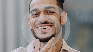 Extreme close-up male portrait outdoors face of bearded hispanic arabic guy brunette man client of barbershop satisfied