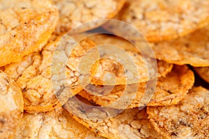 Extreme close up of a pile of organic, crispy, baked, whole grain rice chips with tomato and paprika spices. Gluten free healthy