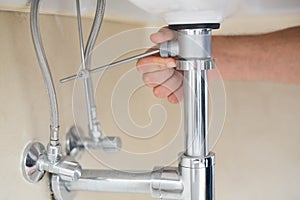 Extreme Close up of a plumber's hand and washbasin drain
