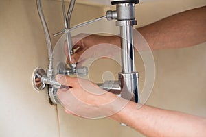 Extreme Close up of a plumber's hands and washbasin drain