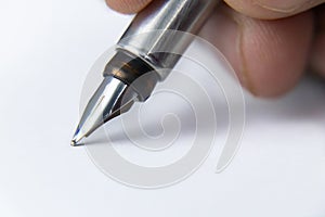 Extreme close up shot of a fountain pen nib put on white paper and fingers holding it -Unique concept