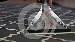 Extreme close-up of unrecognizable housewife male vacuuming dirty and dusty carpet using a wet vacuum cleaner. Concept