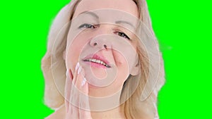 Extreme closeup feminine lips and chin applying anti aging cream on face skin. Women demonstrate moisturizing facial
