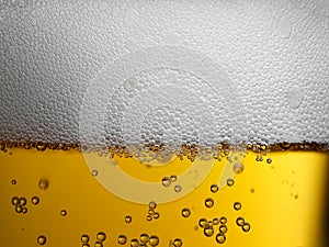Extreme closeup of gold amber beer with frothy head and bubbles photo