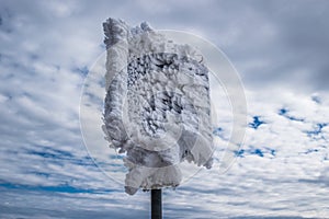 Extreme cold, frozen traffic sign with ice blocks sculpted by gusts of freezing wind