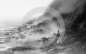 Extreme Crazy Fishing in stormy conditions at Porth Nanven in Cornwall. Waves and sea spray backlit by sun photo