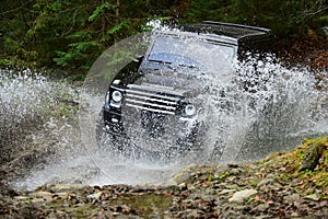 Extreme driving, challenge and 4x4 vehicles concept. Offroad race in forest. SUV or offroad car in black color crossing