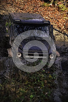 Extreme entertainment concept. SUV covered with mud stuck in puddle