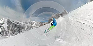 Extreme freeride snowboarder carving down the snowy mountain slope in winter