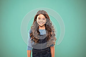 Extreme hair volume. Kid girl long healthy shiny hair. Kid happy cute face with adorable curly hairstyle stand over blue