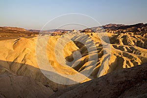 Setting sun on the eroded mountain ridges of desert dry and hot landscape at Zabriskie Point Death Valley National Park, USA