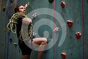 Extreme indoor climbing. Strong man practicing climbing on artificial rock wall